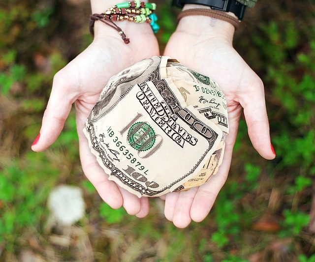 Fundraising is accepting money; here is a ball comprised of hundred-dollar bills. hands open offering a ball of hundred-dollar bills