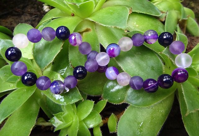 Amethyst-beaded bracelet resting on leaves of a succulent-type plant