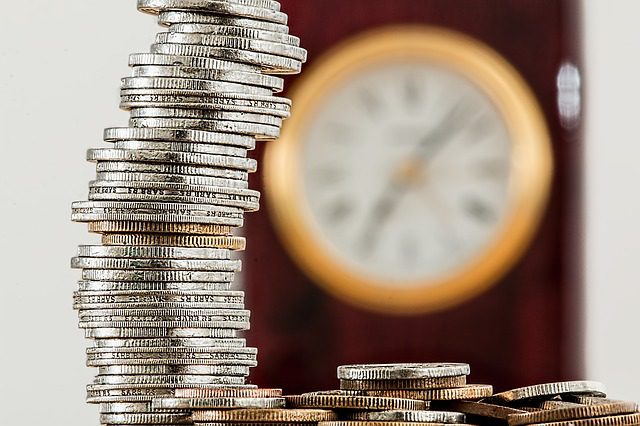 This stack of coins may never be enough to buy back the time you've lost. Time is not money; money wealth can be used to "buy" time. A stack of coins with a clock in the background.