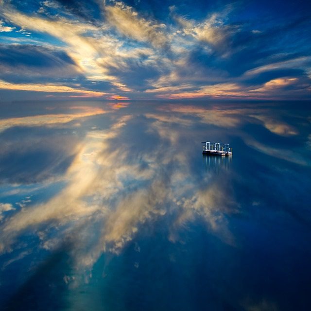 small sturdy raft on an ocean reflecting the sky