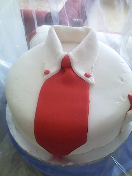 round cake that looks like a button-down shirt with a red tie down its center