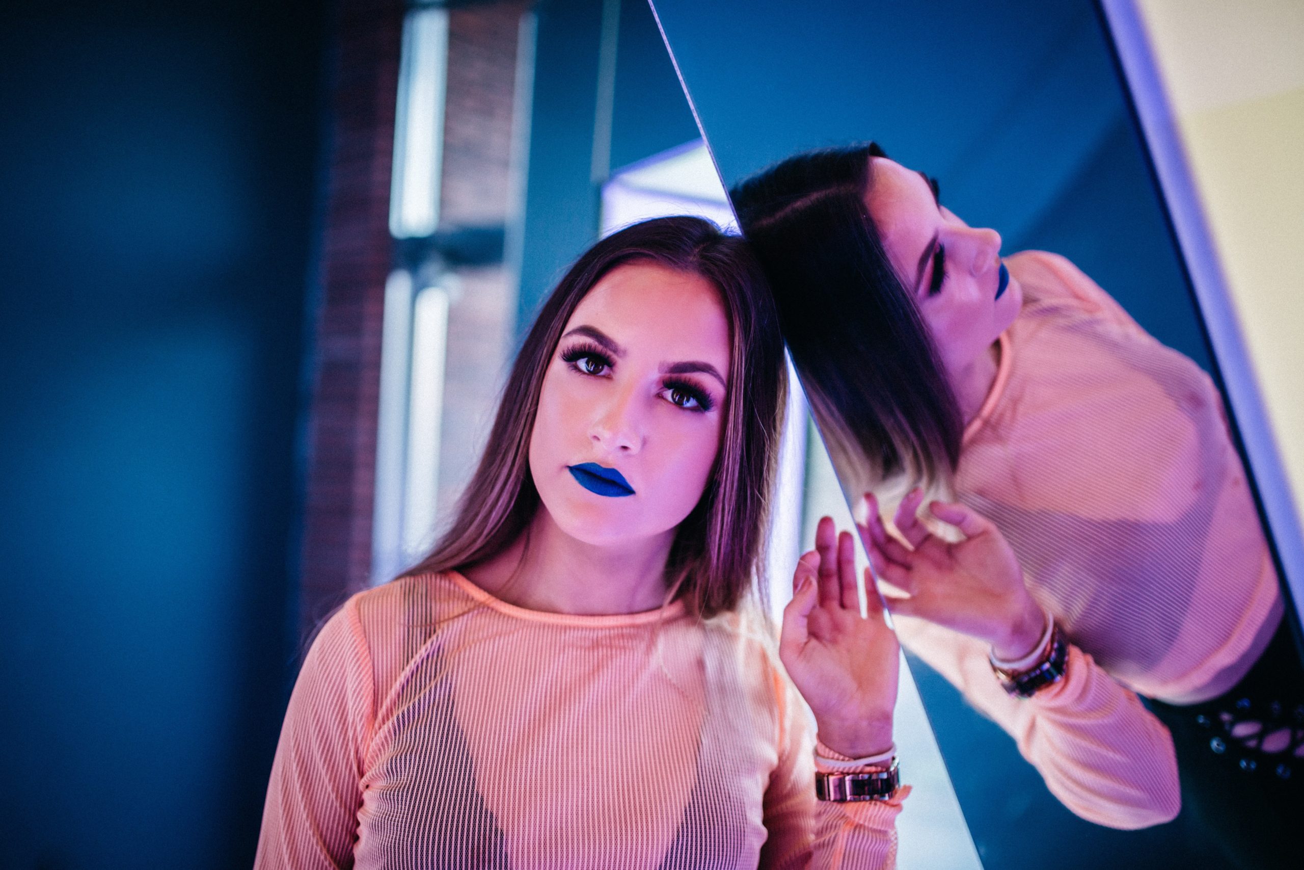 woman leaning against a mirror looking out at the camera pensively